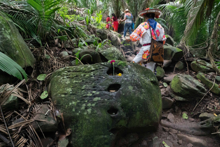 Santos Hernández Ramírez, or Maxatuxame (his name in Wixárika), dressed in a hand-embroidered shirt, guides three Wixárika families through the riverbanks of Altavista, in the municipality of Compostela, Nayarit.