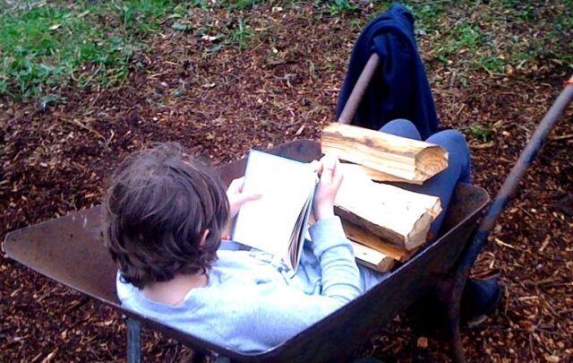 My daughter helps with the firewood while she catches up with her reading.